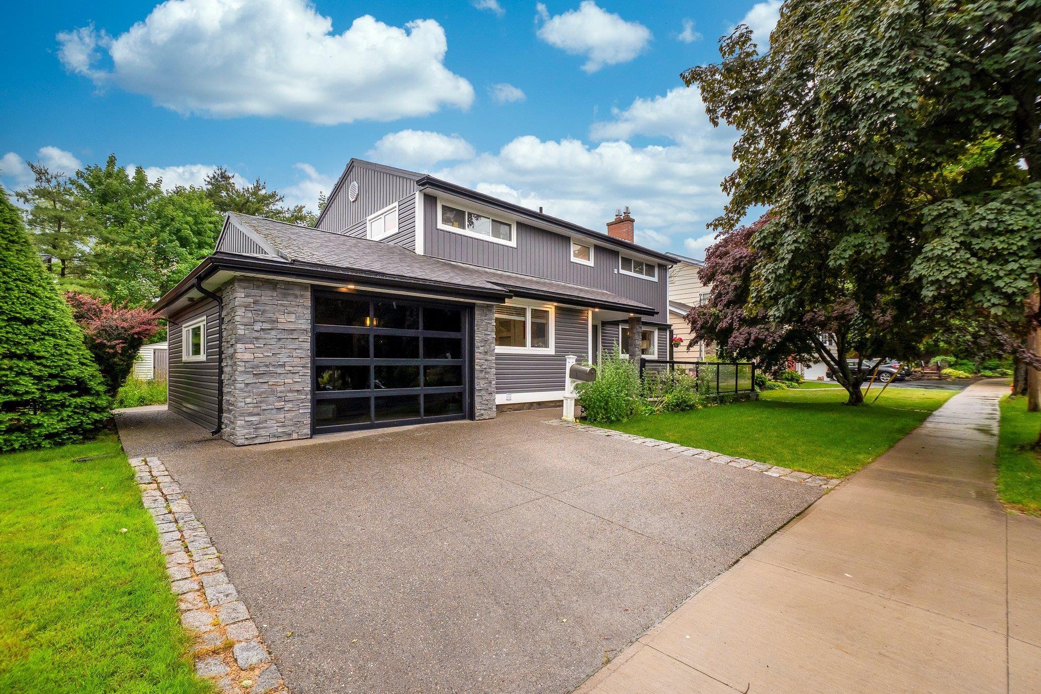 View of front facade featuring stone siding, a front yard, a chimney, driveway, and board and batten siding