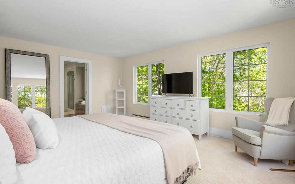 Bedroom featuring multiple windows, light carpet, a baseboard heating unit, and baseboards