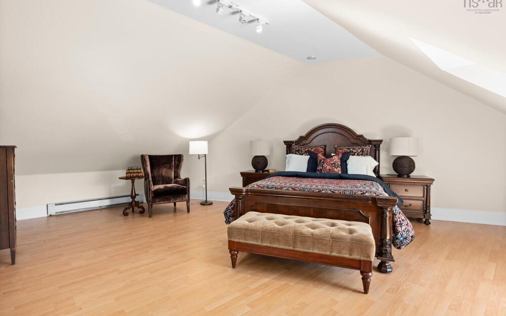 Bedroom featuring a baseboard radiator, light wood-type flooring, vaulted ceiling, baseboards, and a skylight