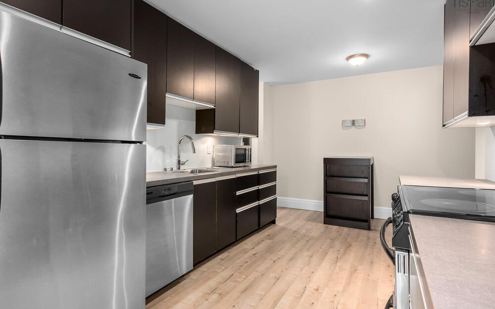 Kitchen featuring appliances with stainless steel finishes, a sink, light wood-style flooring, baseboards, and light countertops