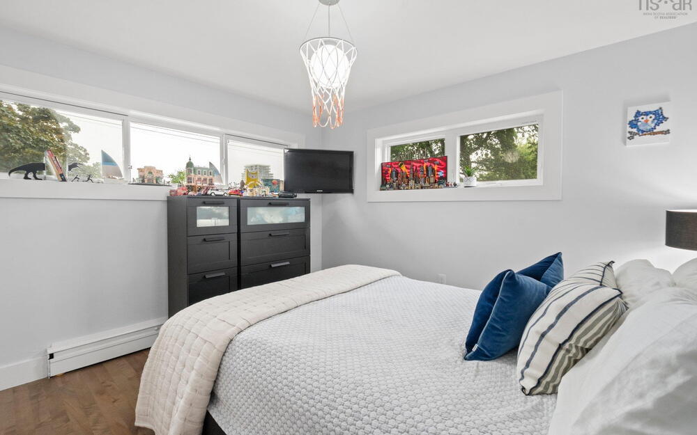 Bedroom featuring a baseboard heating unit, wood finished floors, and a chandelier