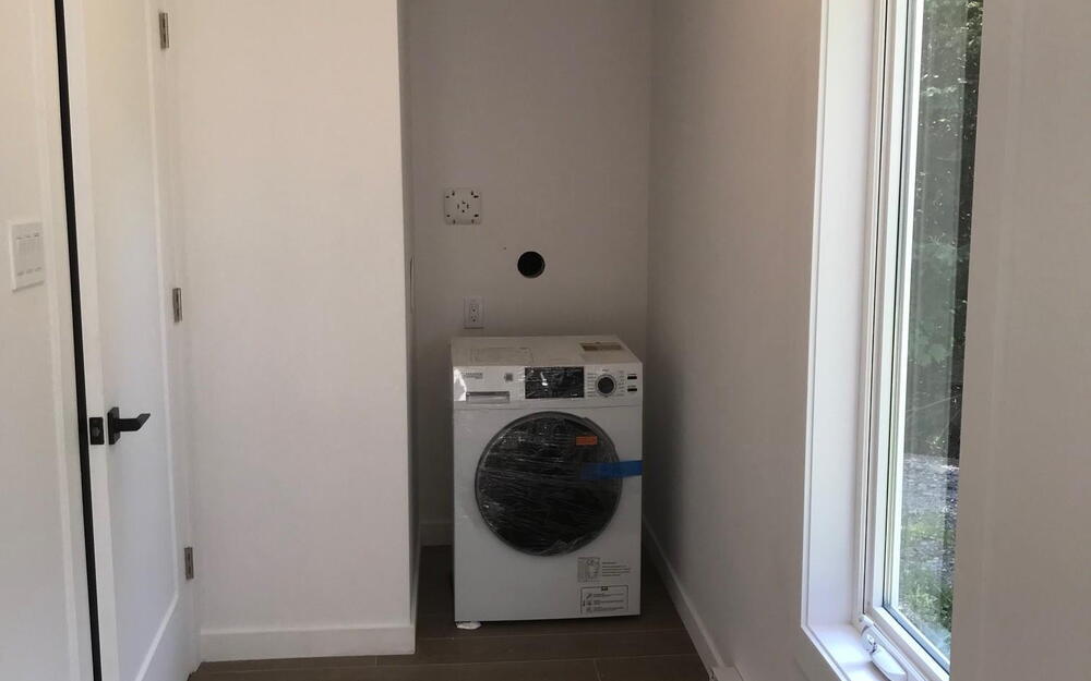 Laundry room featuring washer / clothes dryer, wood tiled floors, and a baseboard heating unit