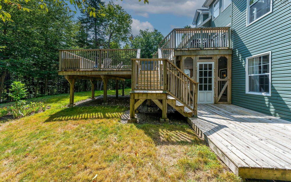 View of grassy yard with a wooden deck and stairway