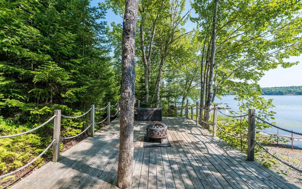 Wooden terrace featuring a water view and an outdoor fire pit