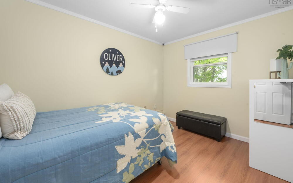 Bedroom featuring wood-finish flooring, a single window, and a ceiling fan with integrated lighting