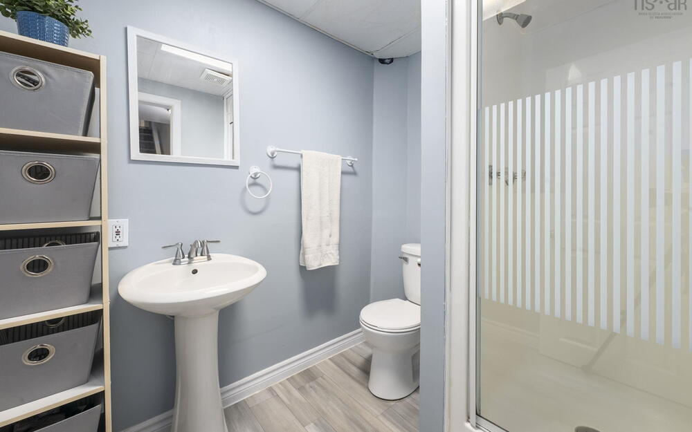 Bathroom featuring a pedestal sink with chrome faucet, a white toilet, and a stand-up shower with a frosted glass door