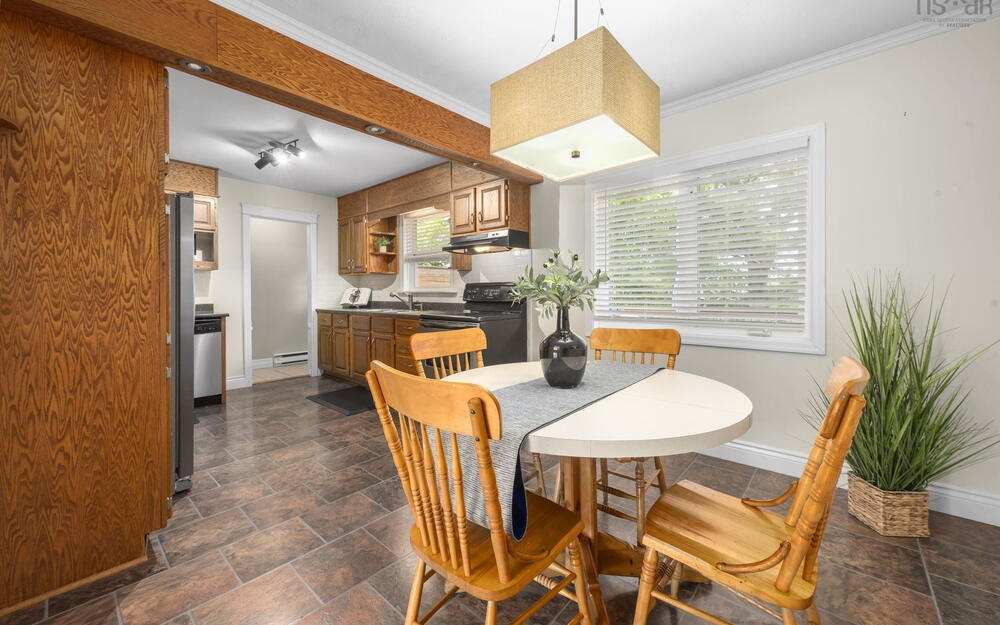 Kitchen and dining area featuring wood-finish cabinetry, dark countertops, and stainless steel appliances