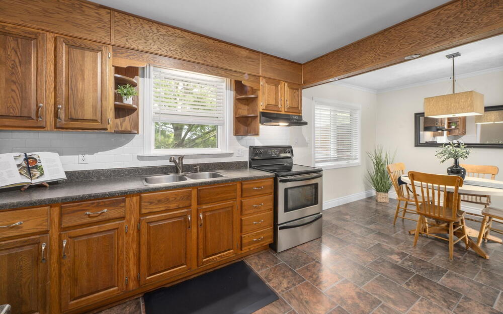 Kitchen and dining area featuring wood cabinetry, stainless steel range, double basin sink, and tile flooring
