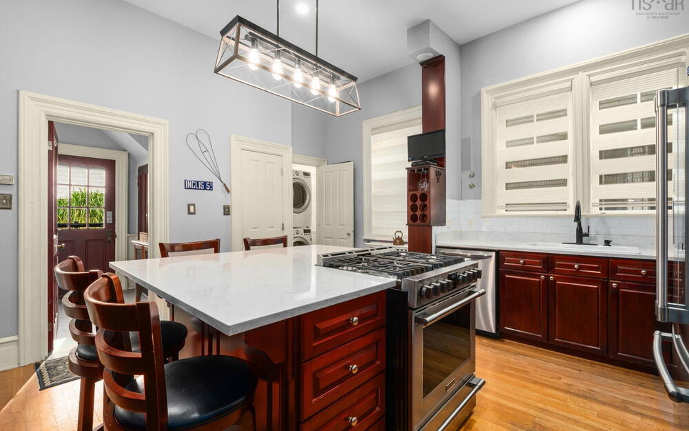 Kitchen featuring a center island with a stone countertop, stained wood cabinetry, stainless steel gas range, built-in wine rack, and pendant lighting