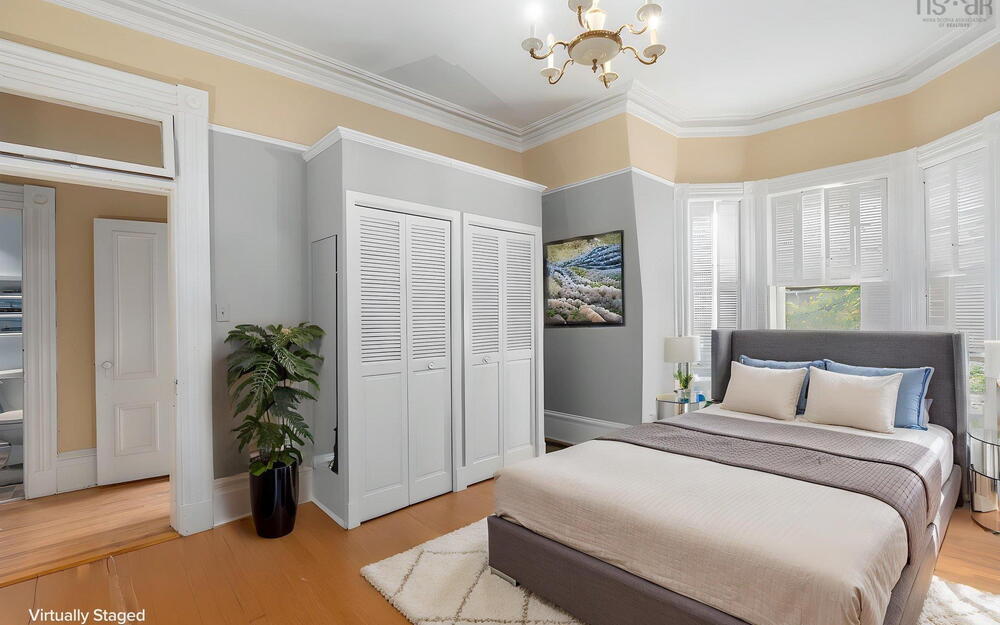 Bay window, crown molding, wood-finish flooring, dual built-in closets with louvered doors, and a multi-arm chandelier