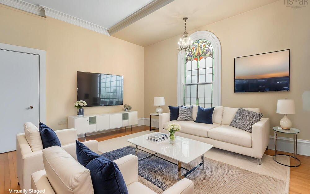 Arched stained glass window with decorative millwork, hardwood flooring, crown molding, and a multi-tiered crystal chandelier