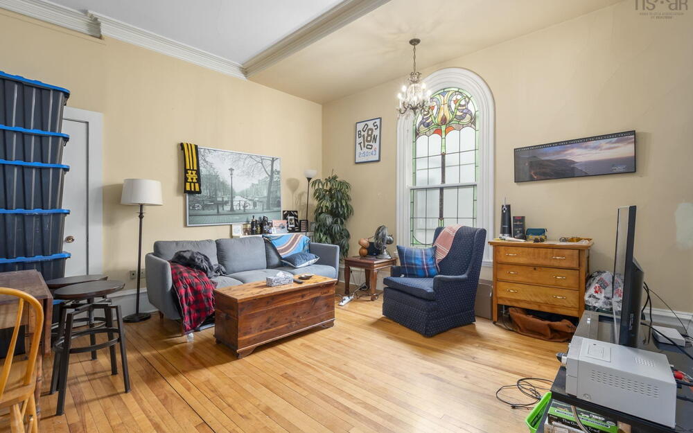 Interior space featuring arched stained-glass window, polished hardwood flooring, crown molding, and tiered chandelier