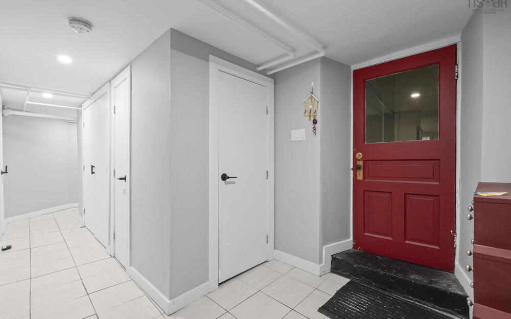 Entryway featuring a red paneled door with a glass insert, light-toned tile flooring, recessed ceiling lighting, and multiple interior doors with matte black hardware